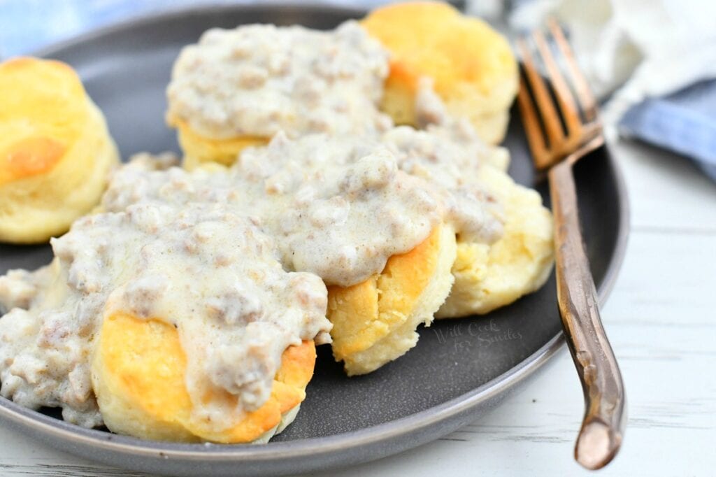 several biscuits covered in sausage gravy on a plate with w bronze fork