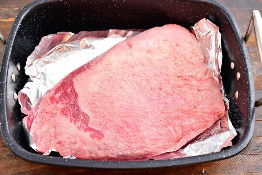 overhead photo: uncooked brisket in large foil-lined roasting pan