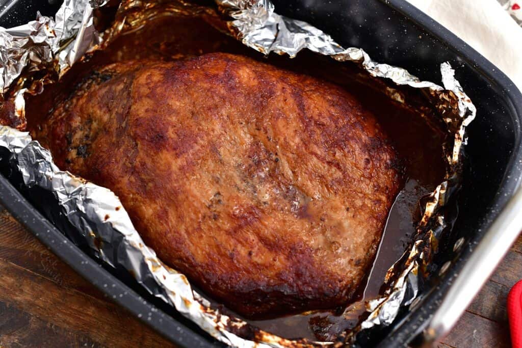overhead photo of beef brisket in roasting pan lined with aluminium foil