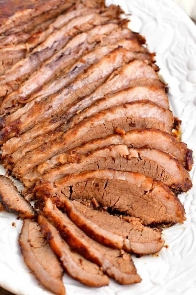 thin slices of oven baked beef brisket on white serving platter