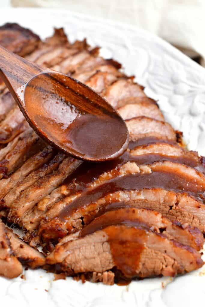 ladling balsamic sauce over tender, thin slices of brisket