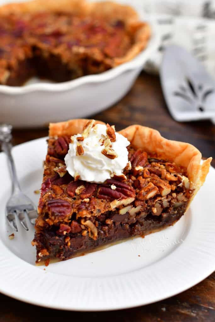 plated slice of chocolate pecan pie topped with whipped cream