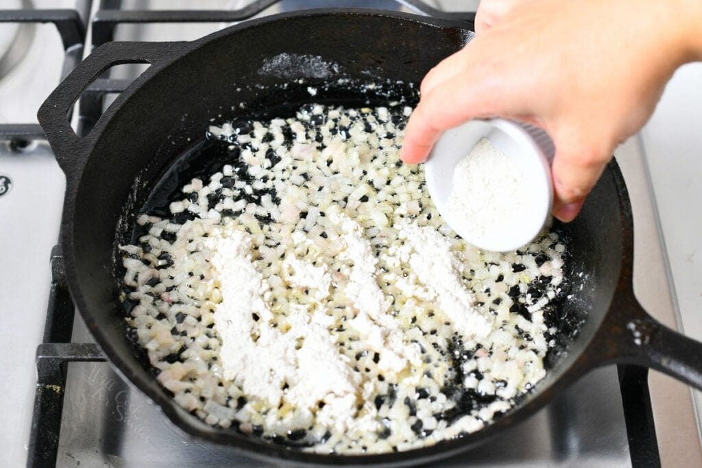 adding white flour to a skillet of buttery onions to make roux