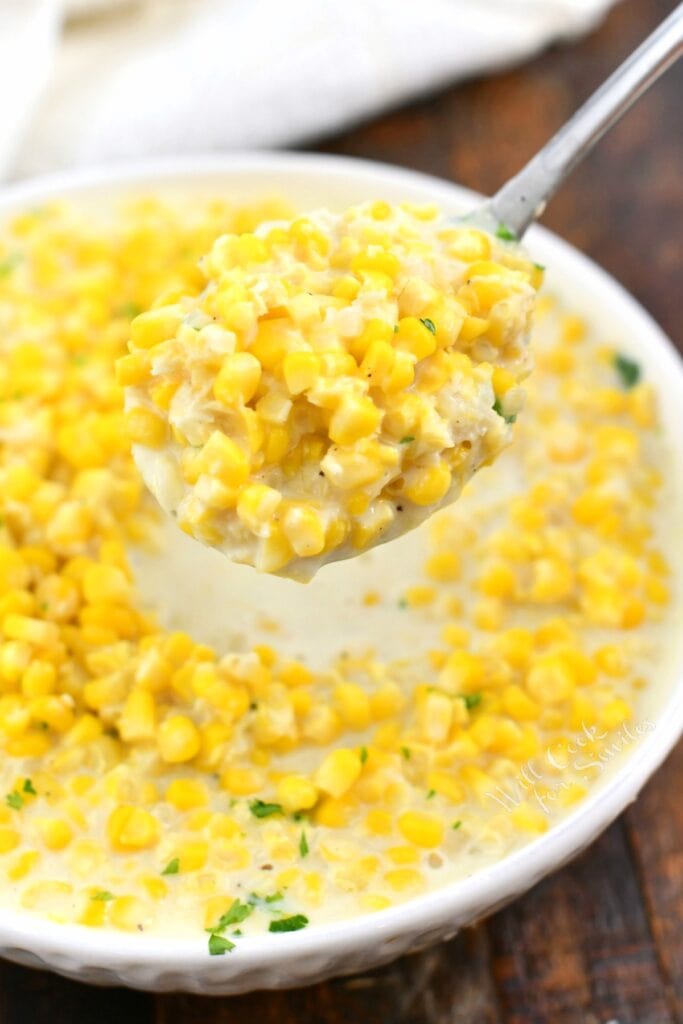 creamy corn side dish in white bowl and on serving spoon above it