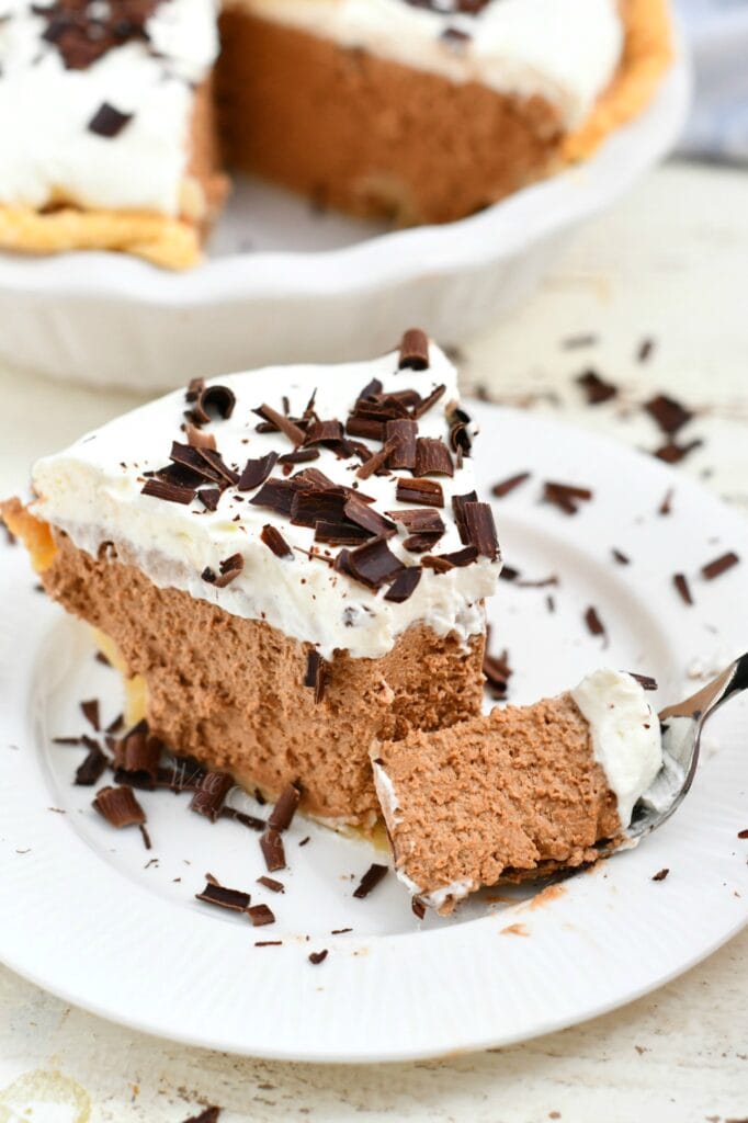 forkful of creamy chocolate pie topped with whipped cream and chocolate shavings