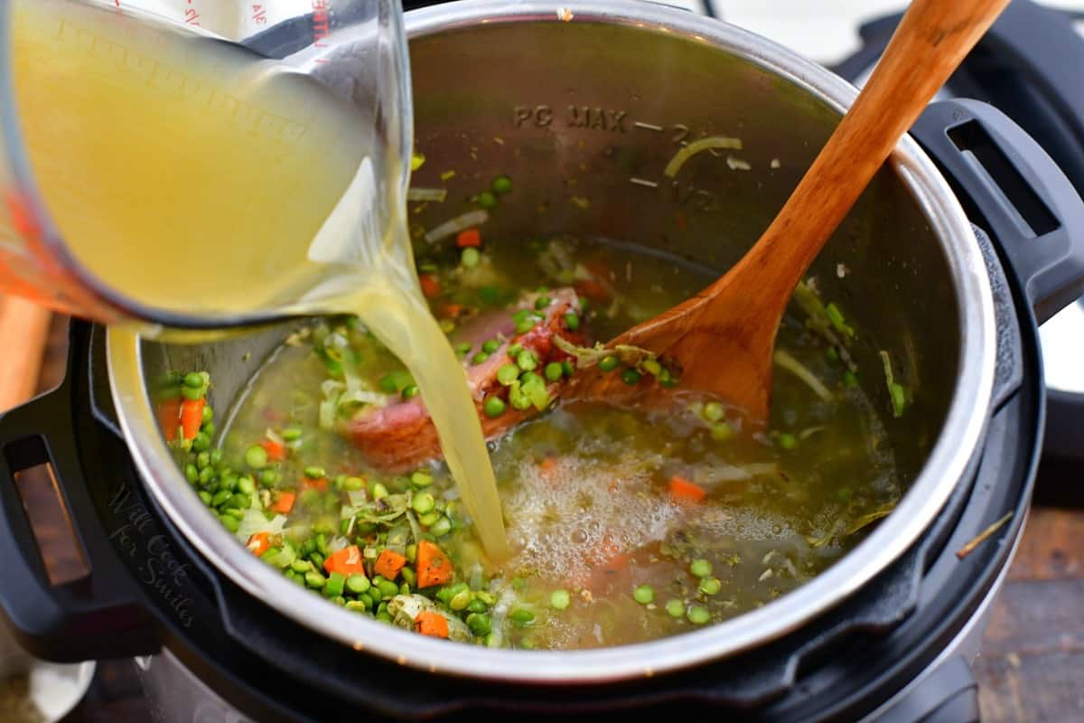 pouring chicken stock into a pressure cooker to make green pea soup recipe.