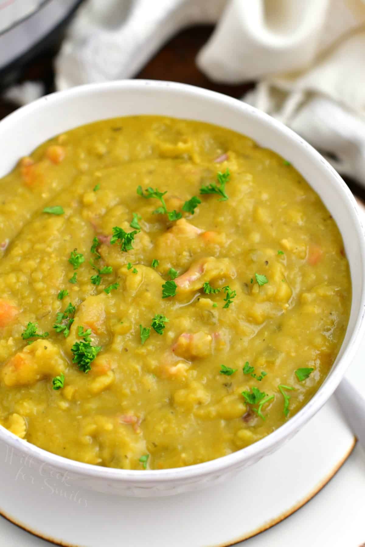 green split pea soup in a white soup bowl and plate.