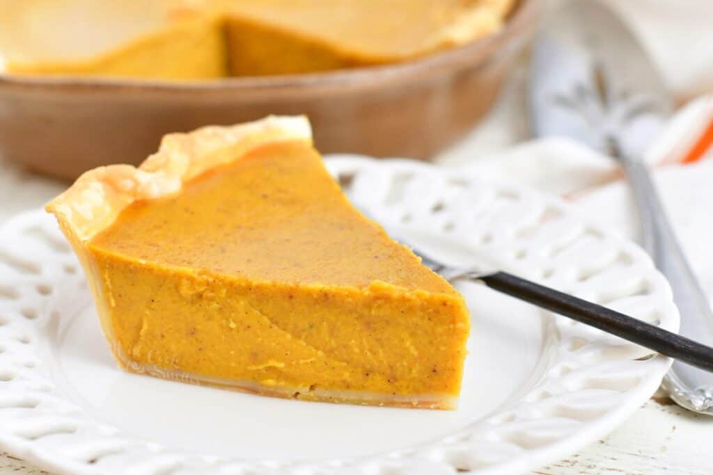 slice of pumpkin pie on a white plate with a fork