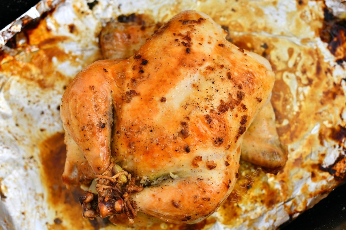 making a roast chicken recipe: trussed bird on sheet of aluminum foil in oven