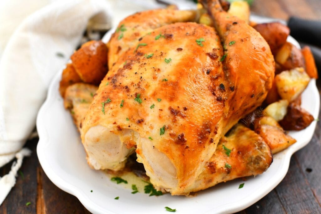 white serving platter of whole roasted chicken with crispy, golden skin