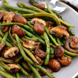green bean and mushroom side dish in white bowl with serving spoon