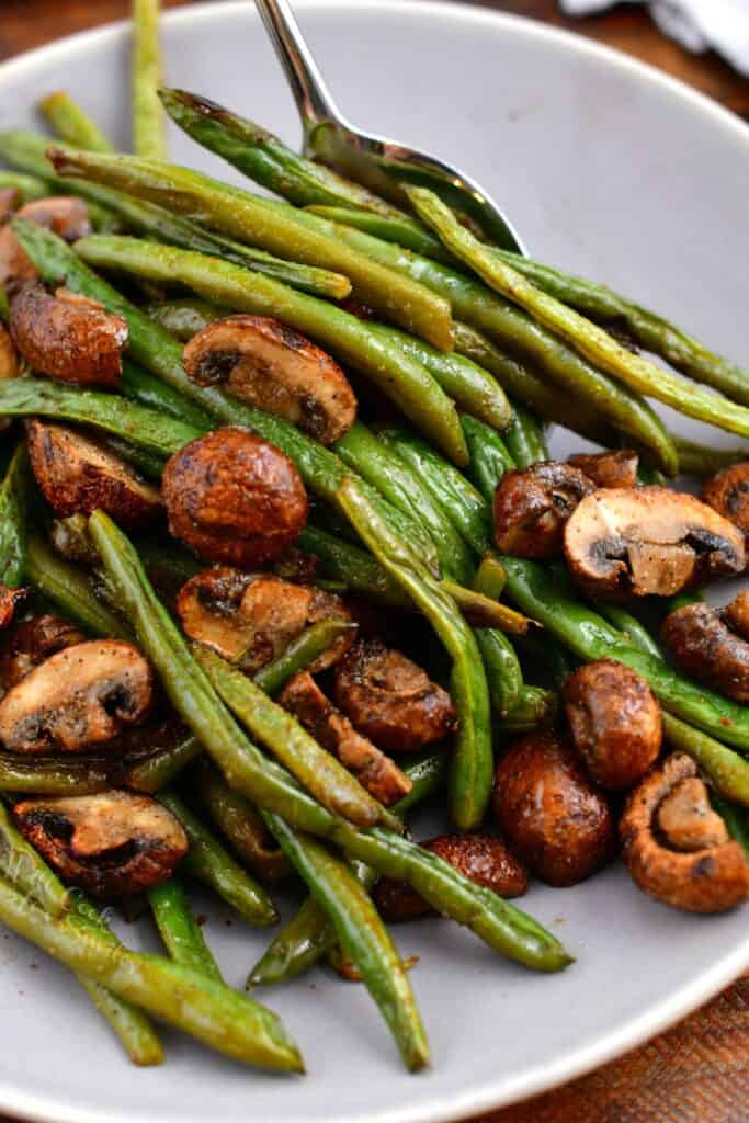 close up overhead photo: white bowl of tender string beans with sauteed mushrooms
