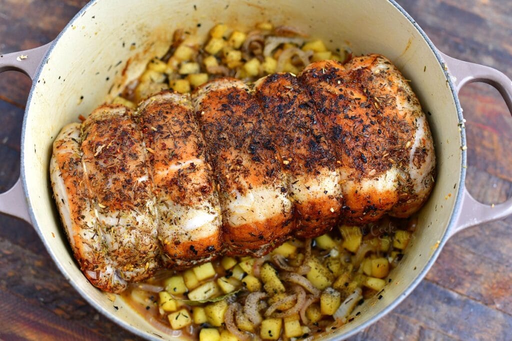 roasting pork loin in white pot with diced vegetables