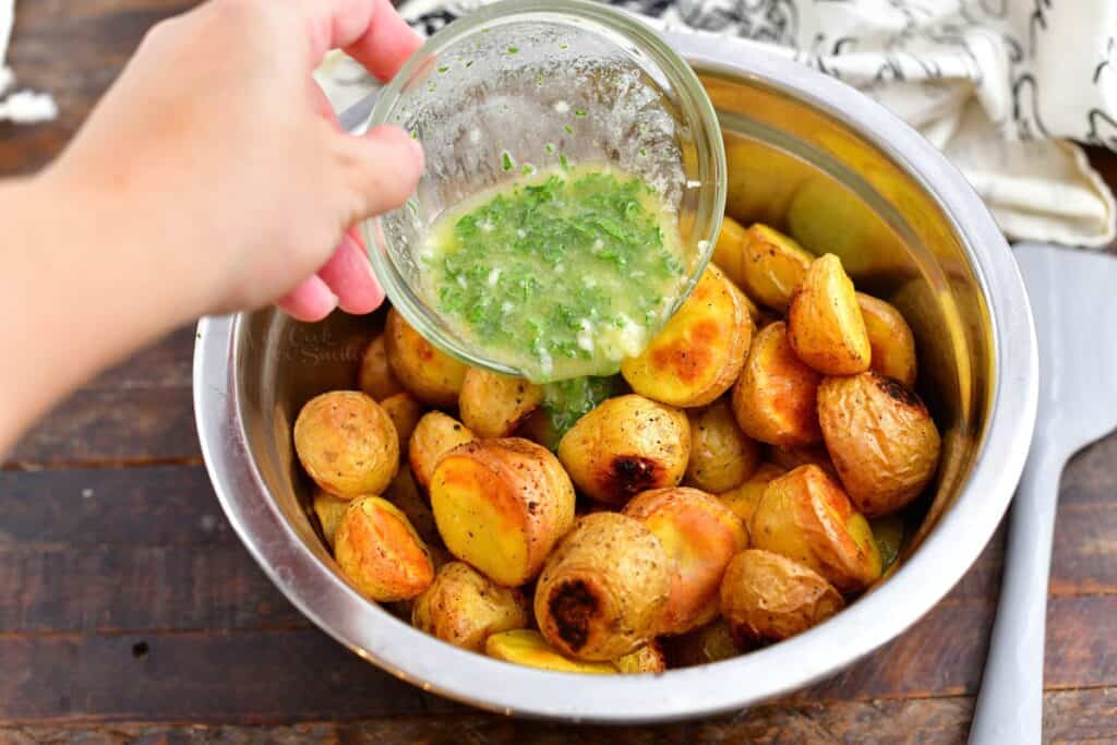 pouring herb butter over cooked potatoes