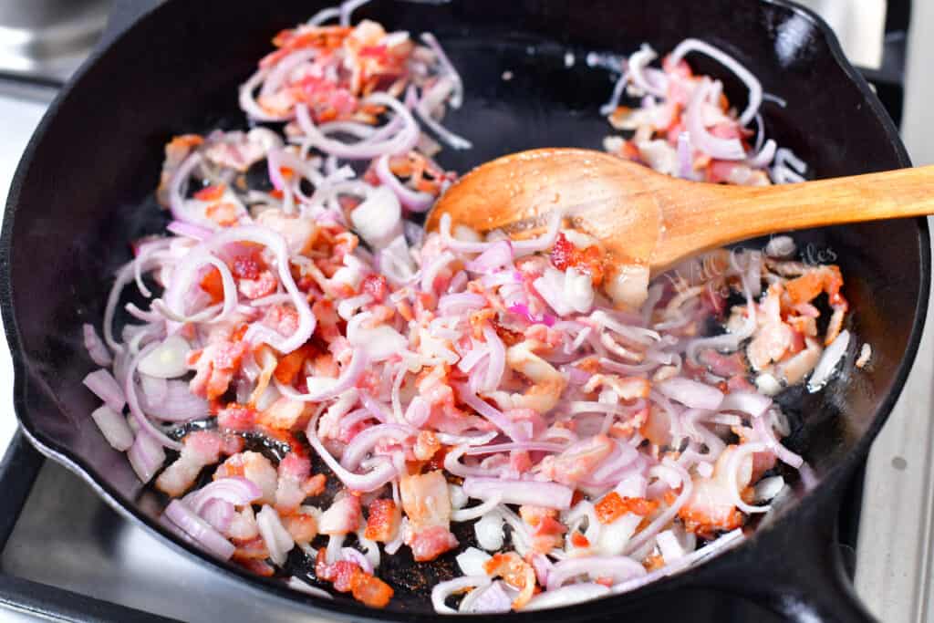 cooking chopped bacon and shallots in a black skillet