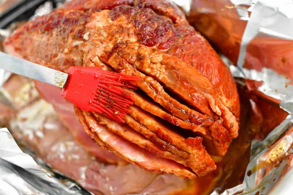 brushing bourbon glaze onto spiral cut ham for baking