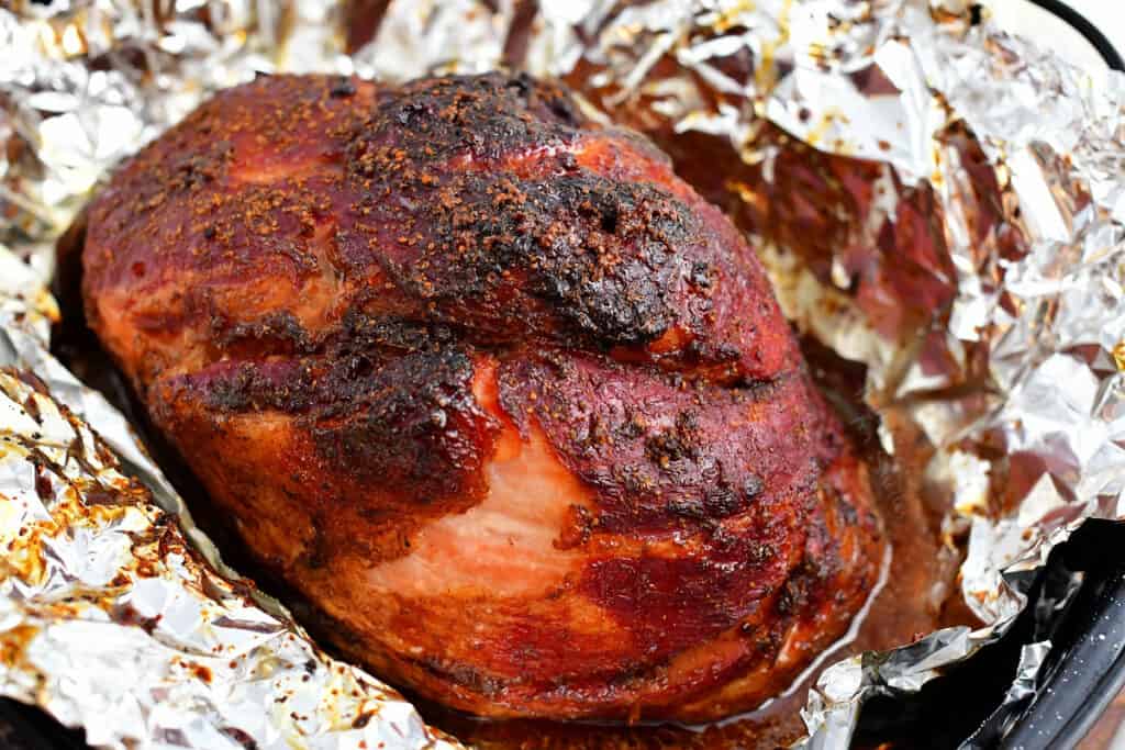 baked bourbon glazed ham on foil lined baking pan