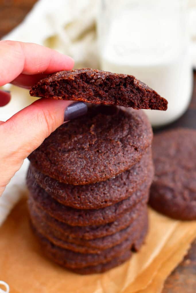 woman's hand holding freshly baked chocolate cookie with bite removed