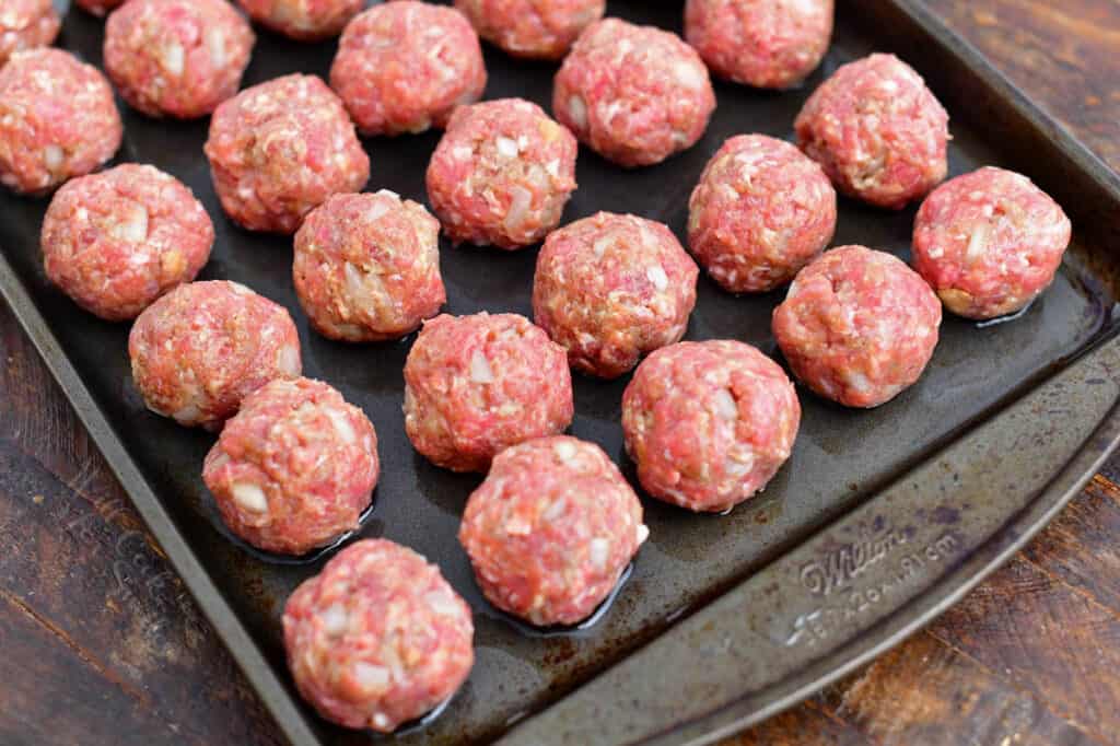 uncooked beef appetizer meatballs on baking sheet