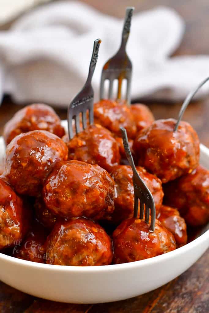 bowl of meatballs with some skewered with appetizer forks