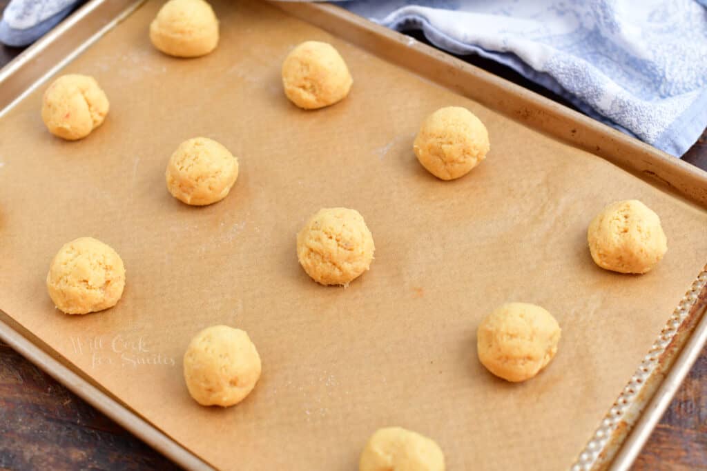 Balls of cookie dough are spread 2 inches apart on a baking sheet.
