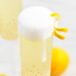 A lemon twist garnishes a French 75 cocktail in tall glass