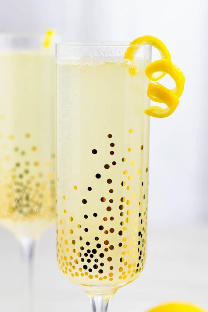 A French 75 is served in a sparkling, golden glass with a sliver of orange peel.