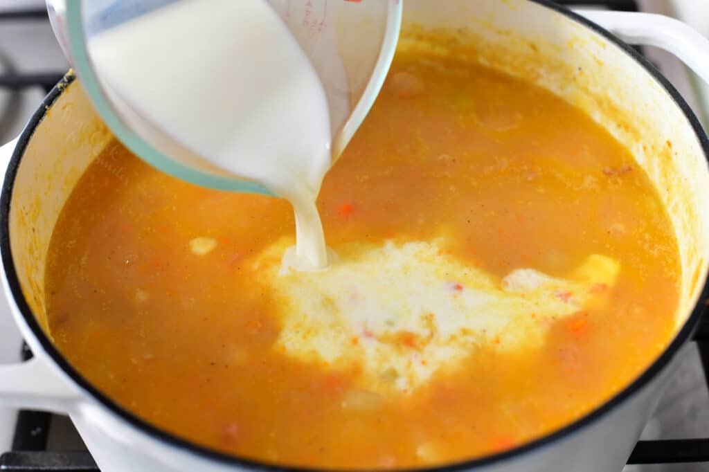 pouring cream into a pot of homemade soup