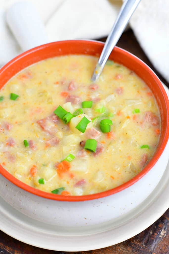 spoon in bowl of creamy potato soup with ham
