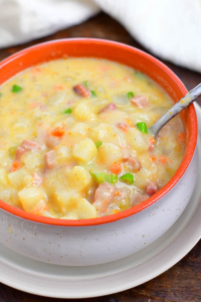 overhead image: spoon in orange bowl of creamy ham chowder