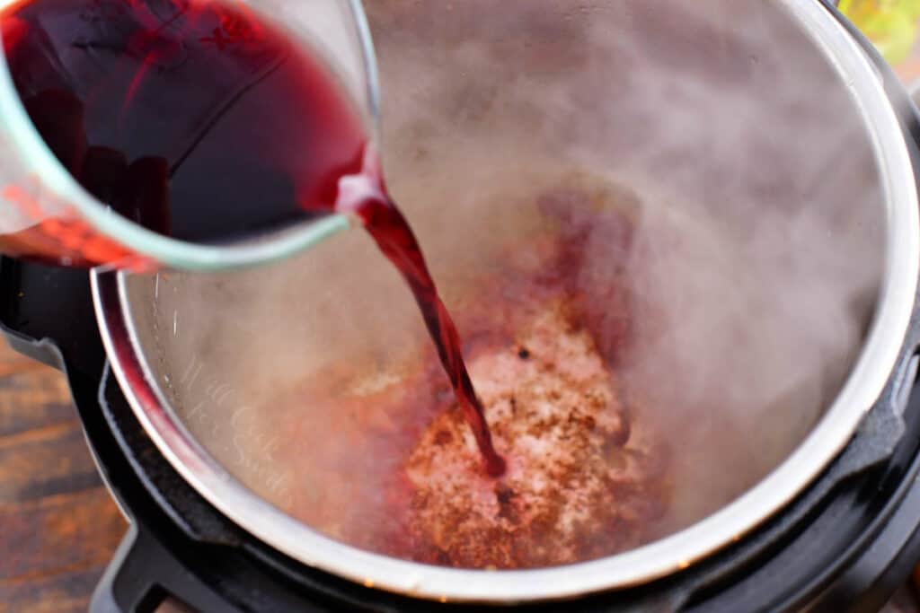 pouring red wine into an instant pot.