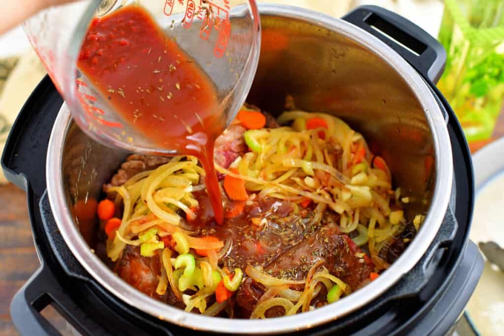 Sauce is poured on top of meat and veegtables in the instant pot.