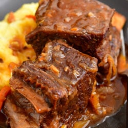 A serving of short ribs is served on top of mashed potatoes.