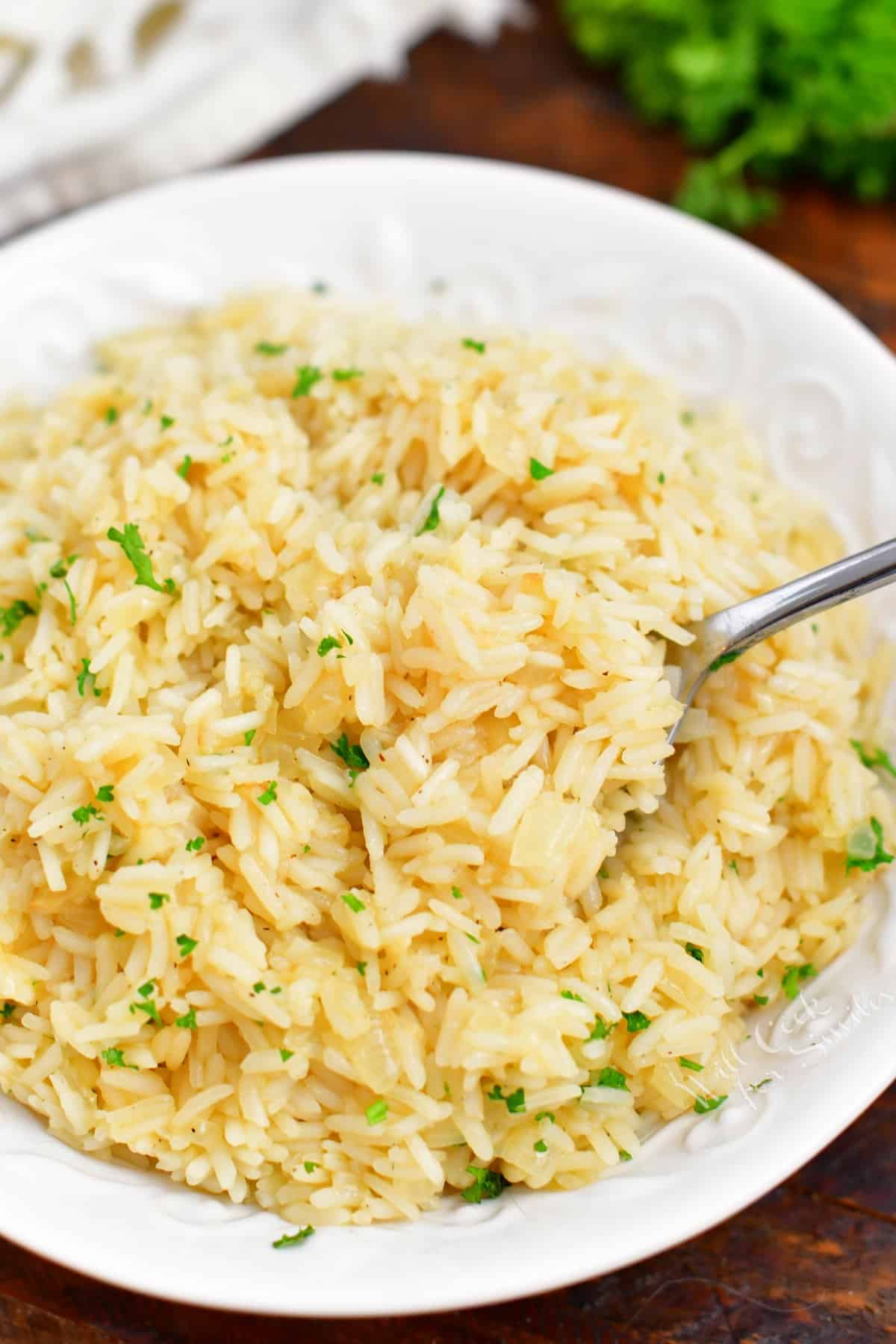 overhead image: spoonful of cooked oven pilaf on spoon in white serving bowl