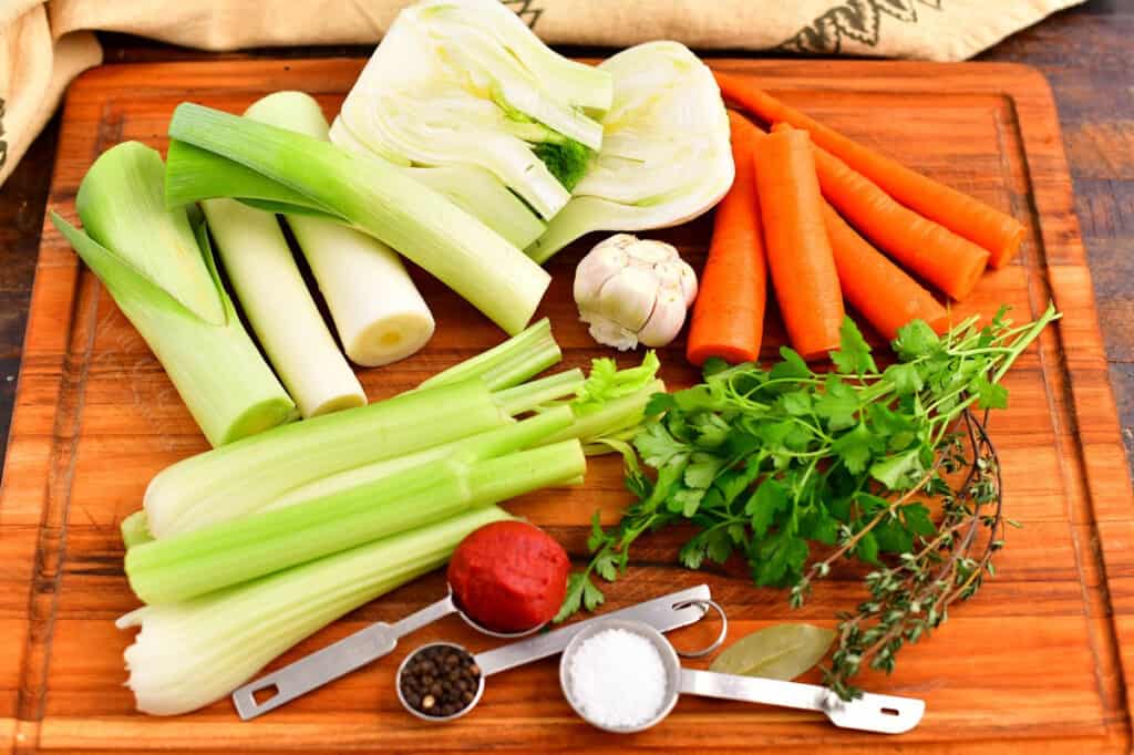 fresh vegetables, herbs, and spices on cutting board to make vegetable stock