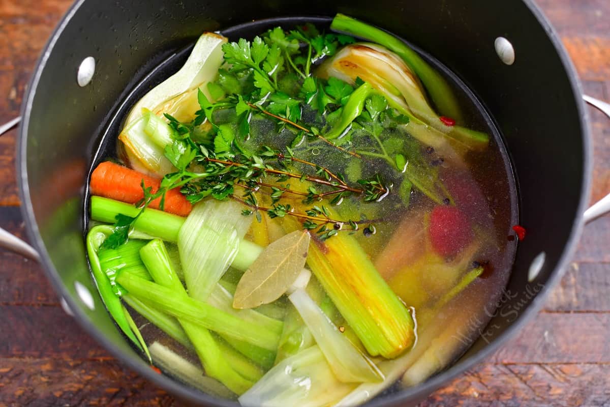 overhead photo: fresh vegetables and herbs cooking in large stock pot to make vegetable broth