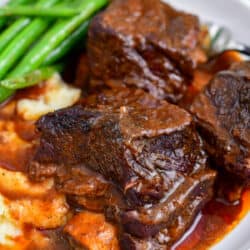 braised beef ribs on plate with green beans and mashed potatoes
