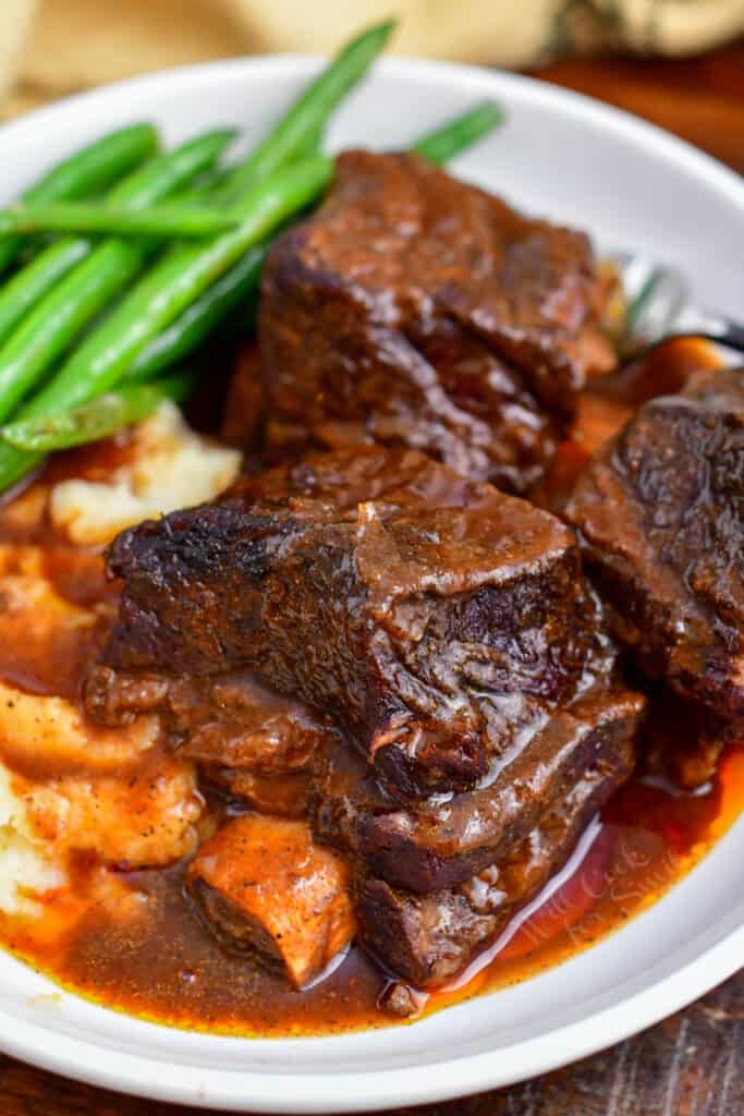 braised beef ribs on plate with green beans and mashed potatoes