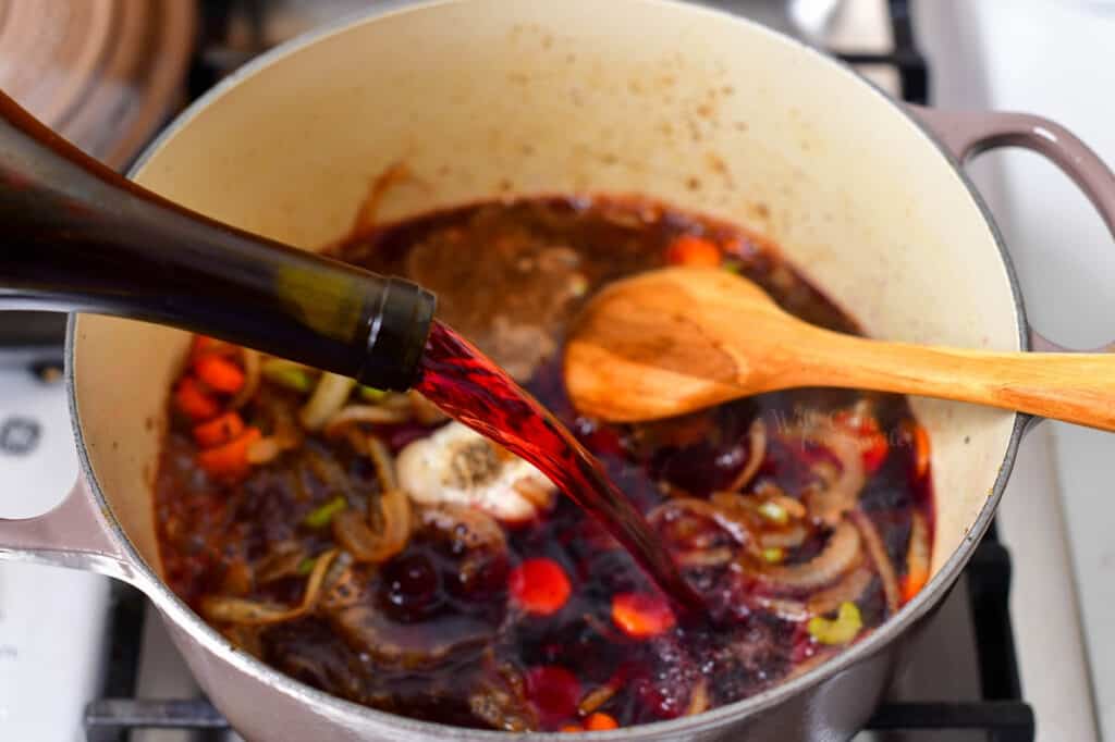 pouring red wine into Dutch oven for a beef short ribs recipe
