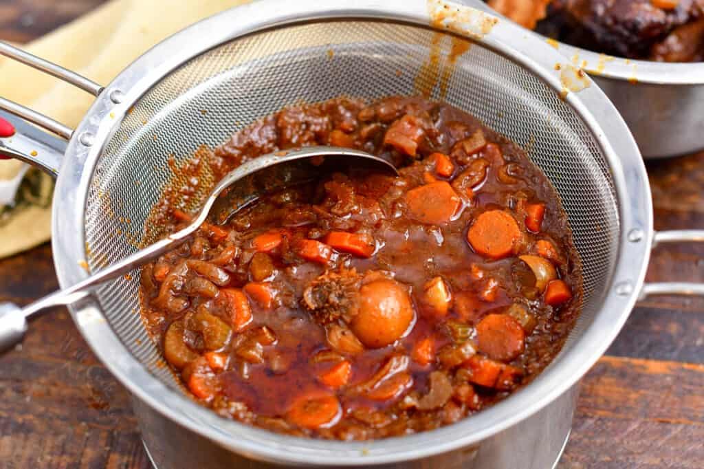 vegetables and braising ingredients in fine mesh strainer