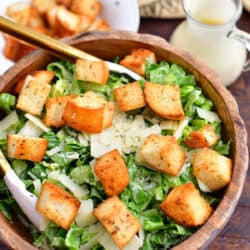 homemade caesar salad with garlic croutons and dressing in wooden bowl