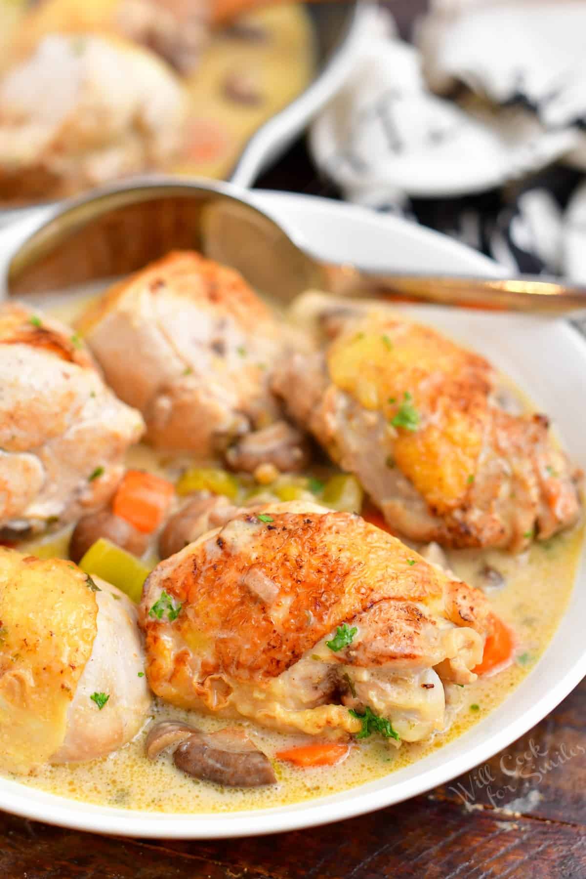cooked meal of chicken thighs and legs with mixed vegetables in creamy white sauce