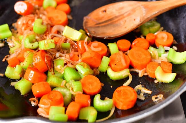 closeup: sauteing slices of carrot, celery and shallot in skillet