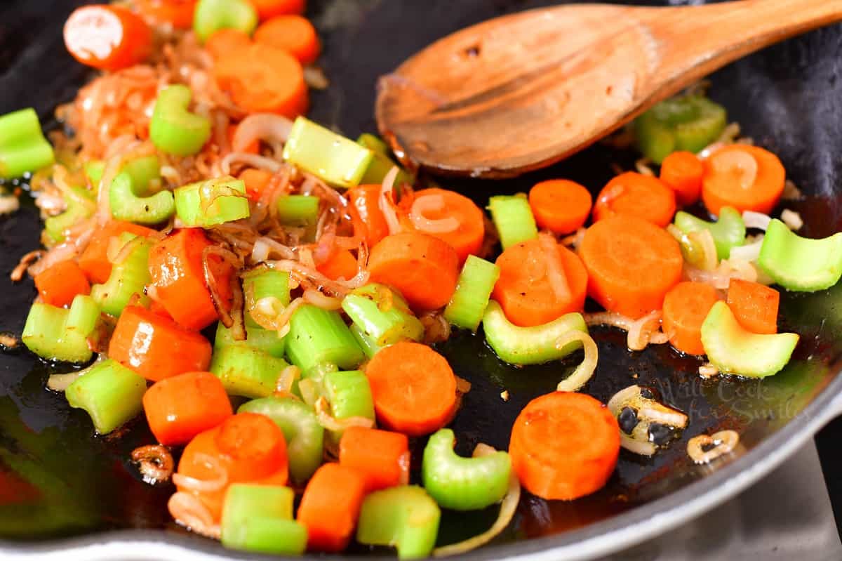 closeup: sauteing slices of carrot, celery and shallot in skillet