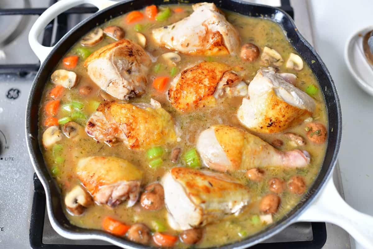 chicken fricassee simmering in white skillet on stove top