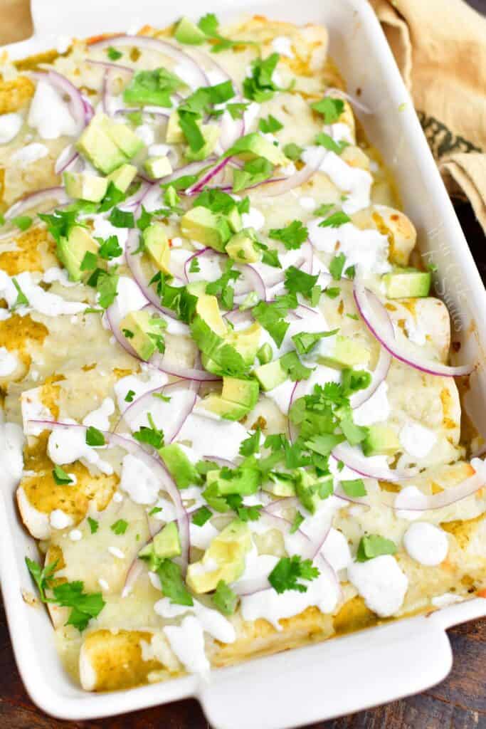 overhead: baked enchiladas verdes in a white casserole dish