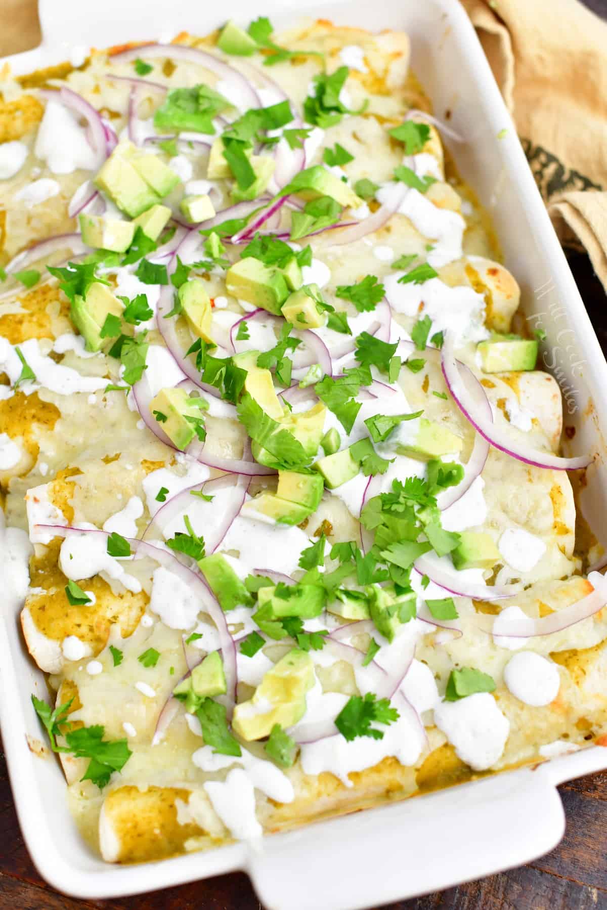 overhead: baked enchiladas verdes in a white casserole dish