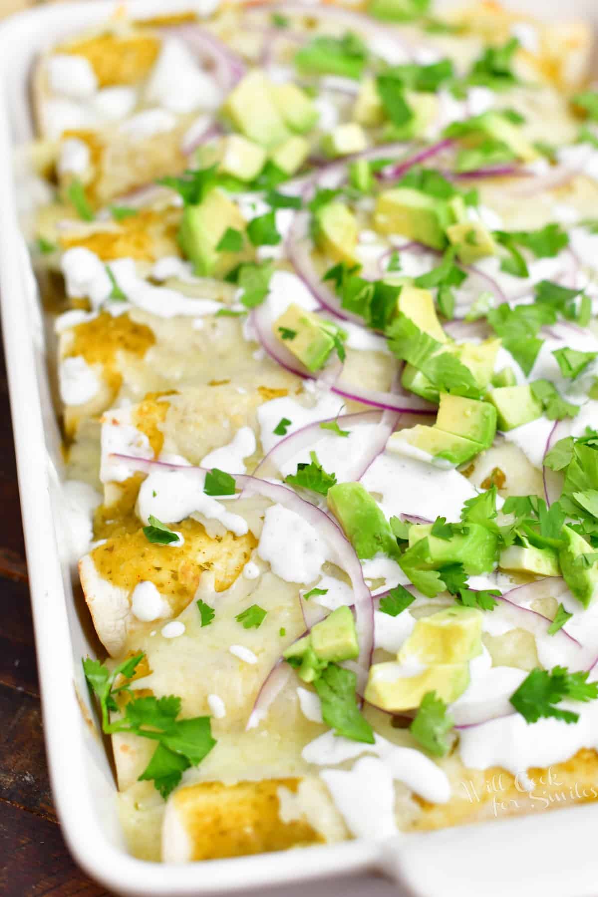 white pan of enchiladas verdes with garnish