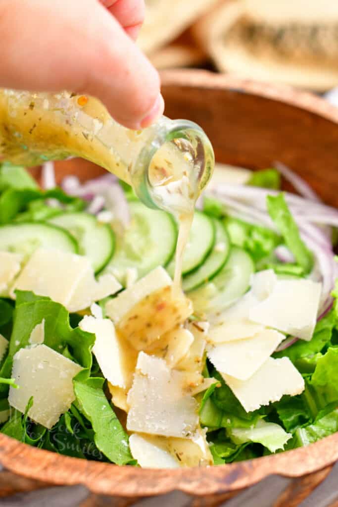 pouring Italian dressing onto a salad
