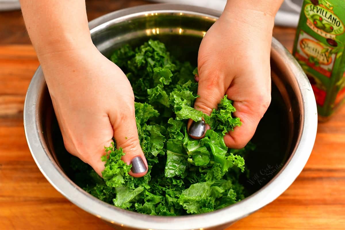 massaging kale in a mixing bowl